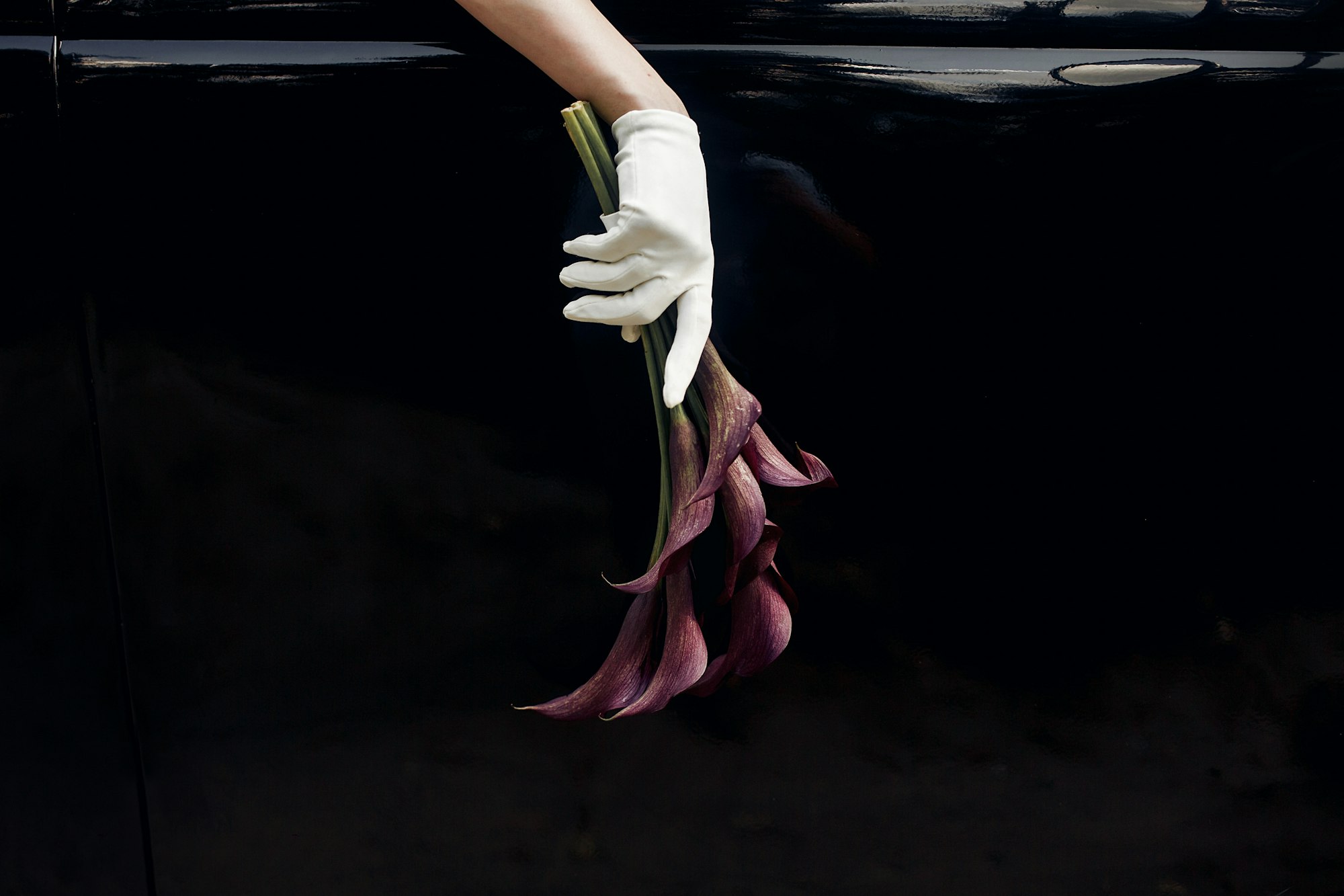 Bride hand in silk glove holding wedding bouquet of callas